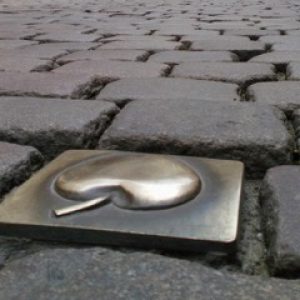 Calle de adoquines con manzana en placa dorada en Sachsenhausen, Frankfurt